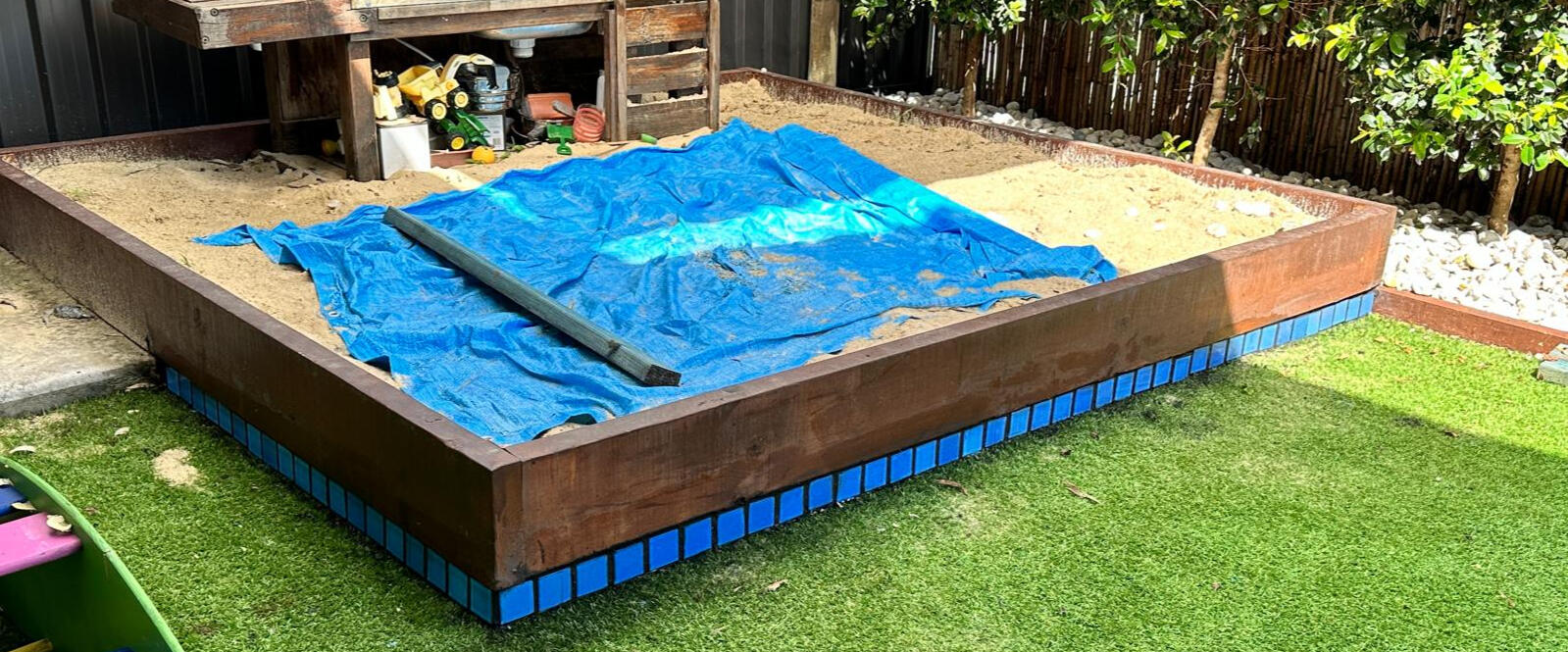Backyard Sandbox Installation by Brett Handyman – Noosa QLD Custom timber-framed backyard sandbox with blue tile edging built by Brett Handyman in Noosa QLD